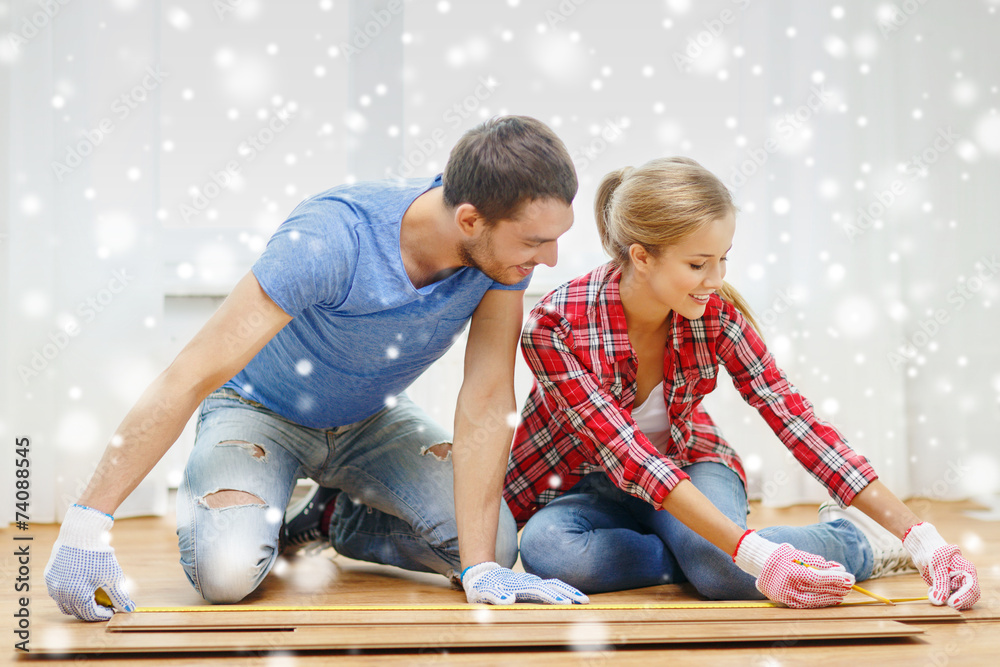 Obraz premium smiling couple measuring wood flooring