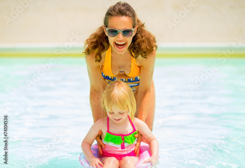 Happy mother and baby girl playing in pool © Alliance