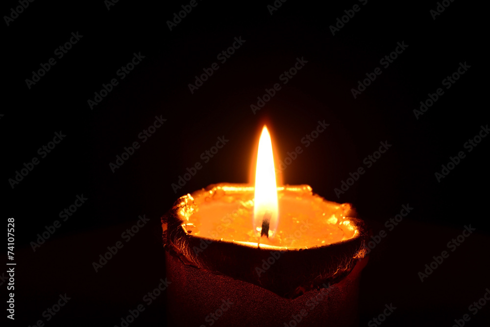 Golden candle burning on a black background Golden candle burning on a black background
