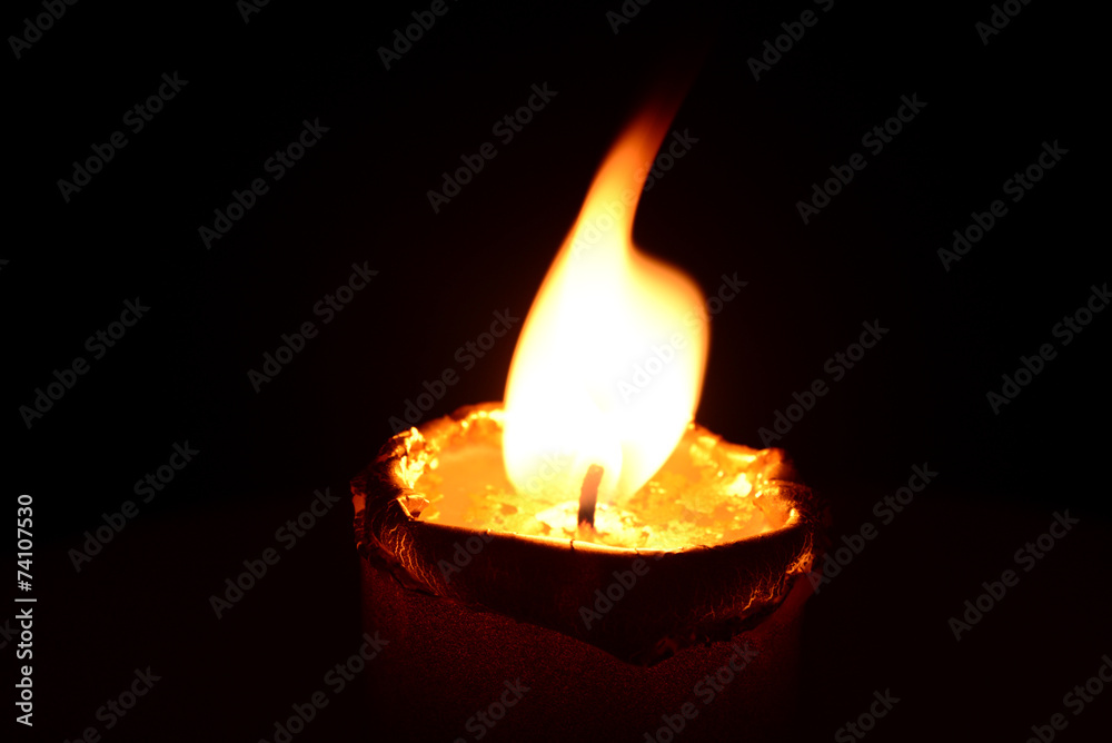 Golden candle burning on a black background Golden candle burning on a black background