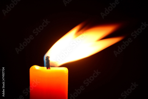 Orange candle burning on a black background