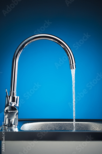 mixer tap with flowing water, blue background