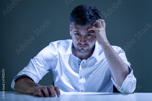 Worried young man sitiing at the table photo