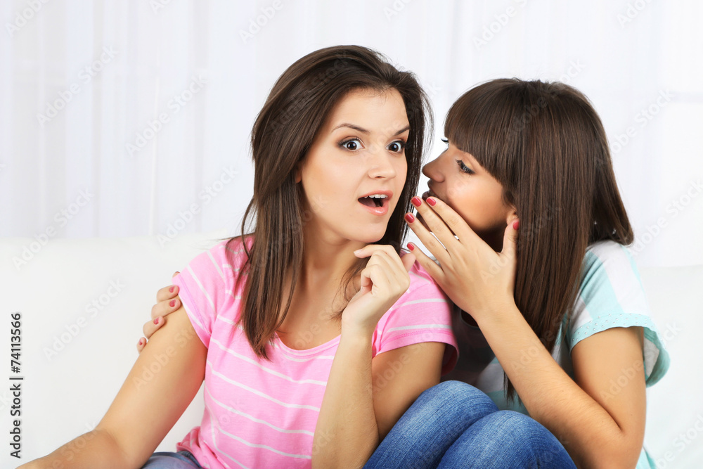 Beautiful girls twins sitting on sofa in room Beautiful girls twins sitting on sofa in room