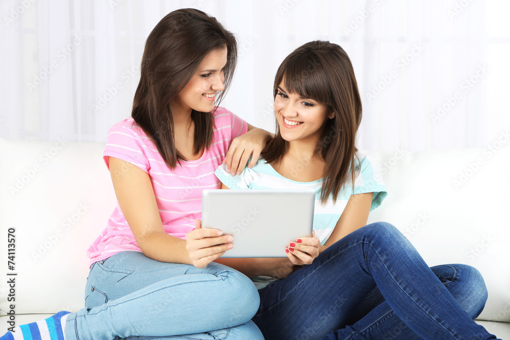 Beautiful girls twins with electronic tablet on sofa Beautiful girls twins with electronic tablet on sofa