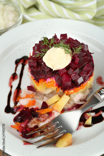 Russian herring salad on plate on wooden table background