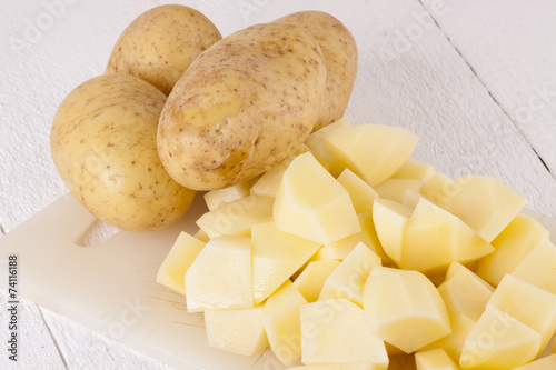 Fototapeta Naklejka Na Ścianę i Meble -  Whole Potatoes and Chopped Pieces on Cutting Board