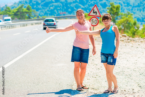 two friends Hitchhiking summer in the mountains photo