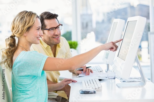 Cheerful photo editor pointing at a computer