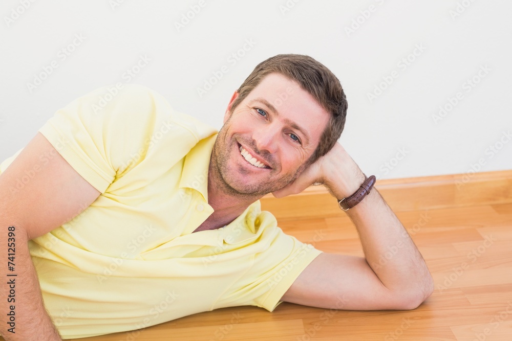 Smiling man lying on the floor at home Smiling man lying on the floor at home