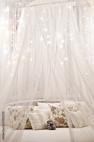 Obraz na płótnie White cozy bed with vintage pillow and christmas lights w salonie