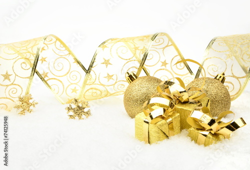 Golden christmas gifts,baubles with golden ribbon on snow photo