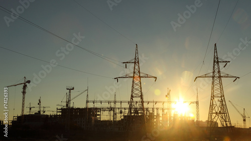 silhouettes of construction and power lines at sunset