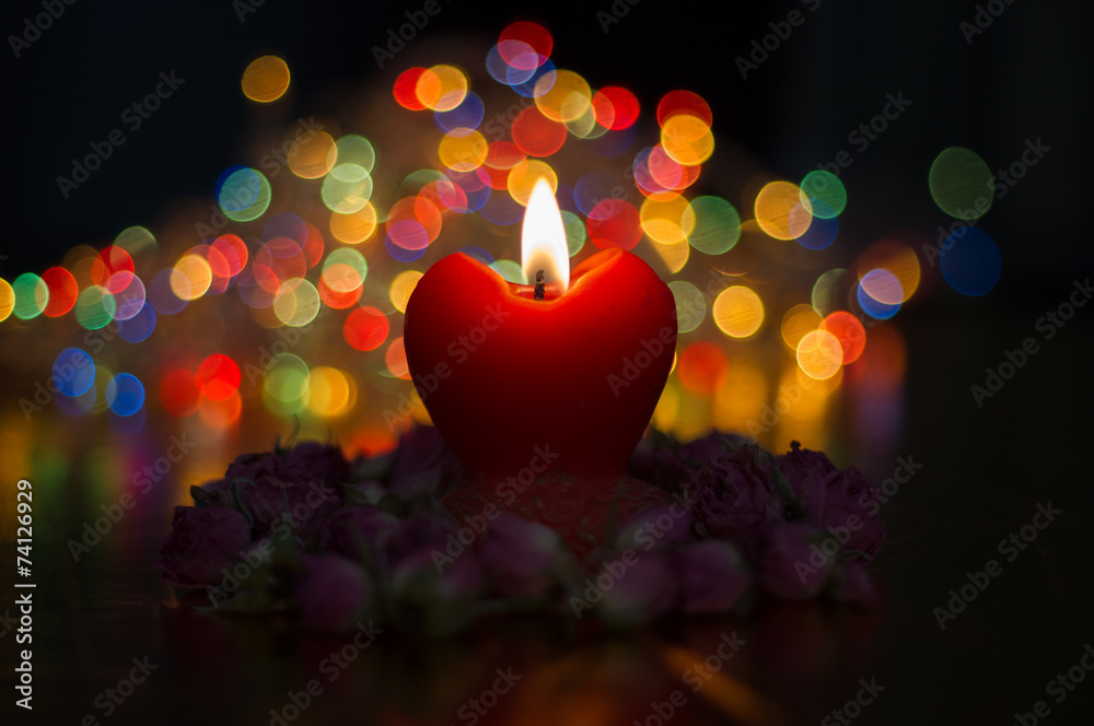 Red heart candle with roses on mistical colored lights