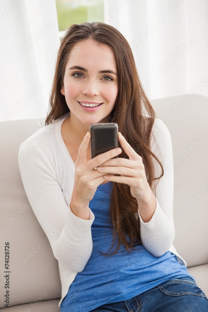Pretty brunette sending a text on the couch Pretty brunette sending a text on the couch