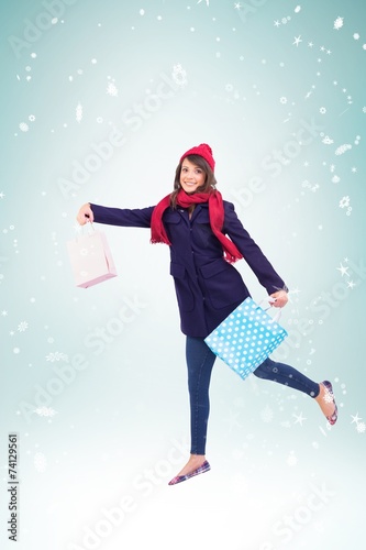 Composite image of festive brunette holding shopping bags