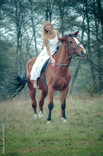 romantic sensual girl in white dress on a horse in the forest