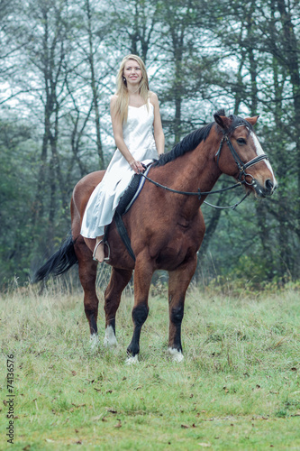 romantic sensual girl in white dress on a horse in the forest
