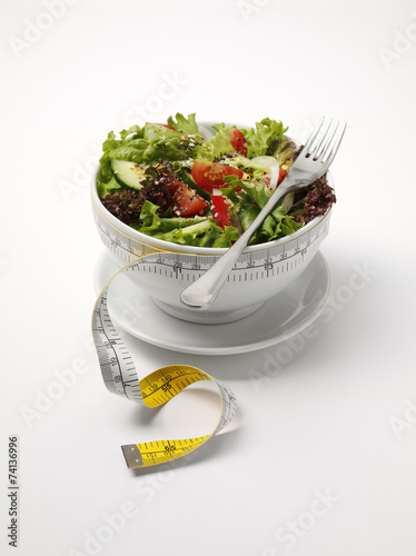 A bowl of mixed salad with a tape measure for healthy eating