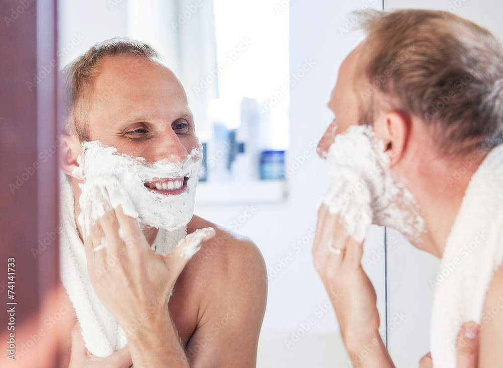 Shaving man near the bathroom mirror