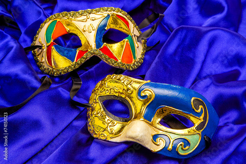 Two colorful Mardi Gras Masks on blue silk