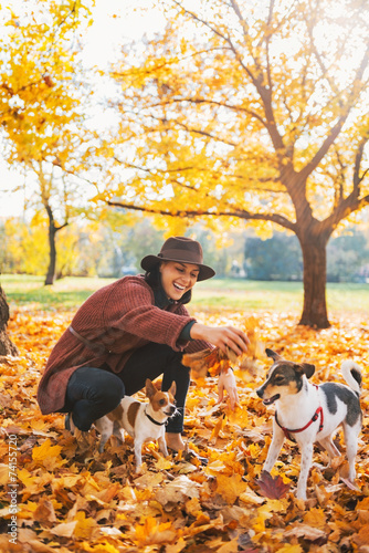 Happy young woman playing with dogs outdoors in autumn