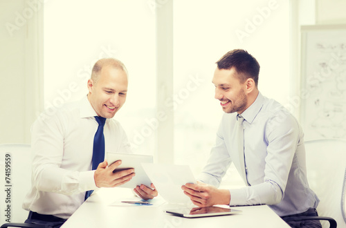 two smiling businessmen with tablet pc in office