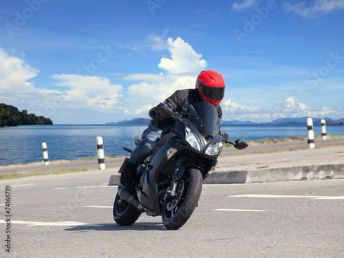 young man riding big bike motorcycle against sharp curve of asph photo