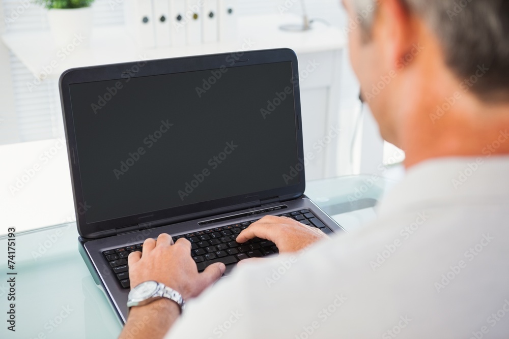 Man with grey hair typing on laptop