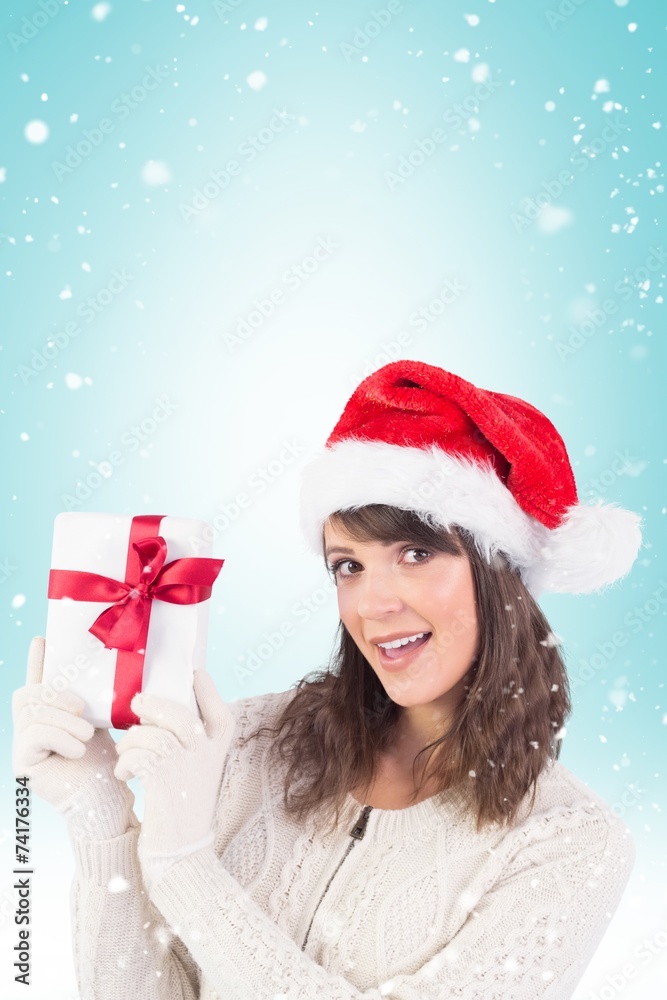 Composite image of festive brunette showing a gift Composite image of festive brunette showing a gift