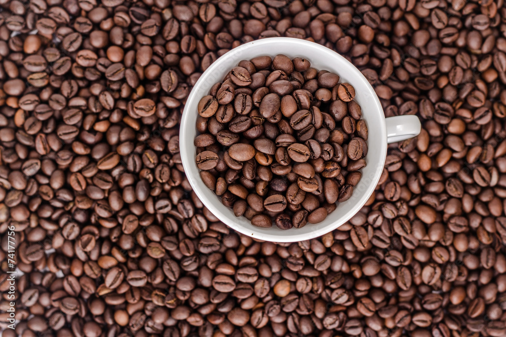 Cup with coffee beans on background of coffee bean, top view Cup with coffee beans on background of coffee bean, top view
