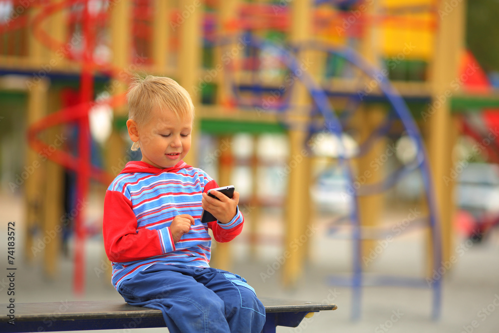 boy with a mobile phone is playing on the playground boy with a mobile phone is playing on the playground
