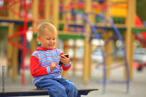 boy with a mobile phone is playing on the playground