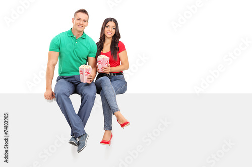 Couple holding popcorn seated on a blank panel