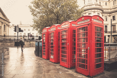 Vintage style  red telephone booths on rainy street in London