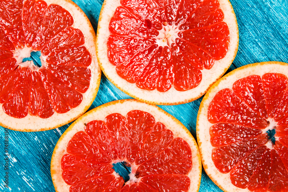 Red grapefruit slices on blue wooden background Red grapefruit slices on blue wooden background