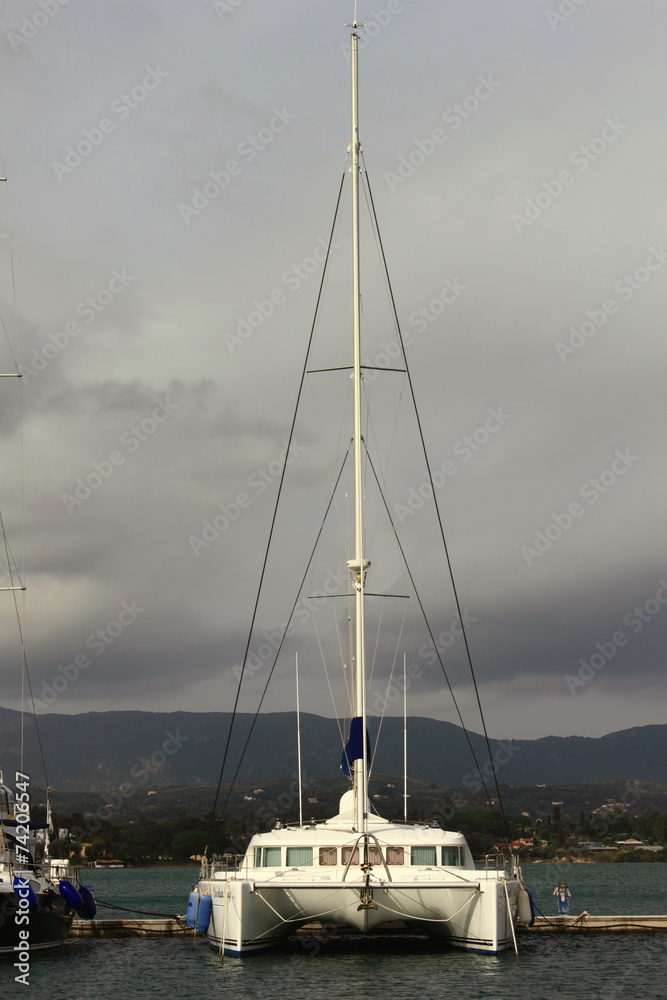 Catamaran moored in marina with grey storm sky Catamaran moored in marina with grey storm sky