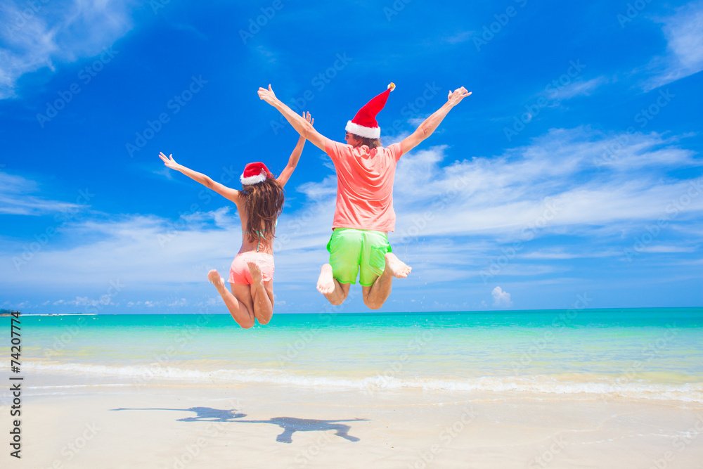 young couple in santa hats laughing on tropical beach. new year young couple in santa hats laughing on tropical beach. new year