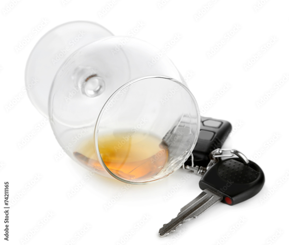 Glass of alcoholic drink and car key, isolated on white