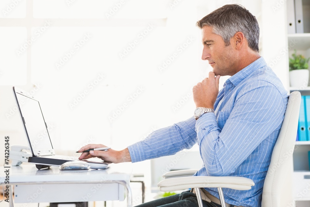 Man in shirt using laptop and thinking