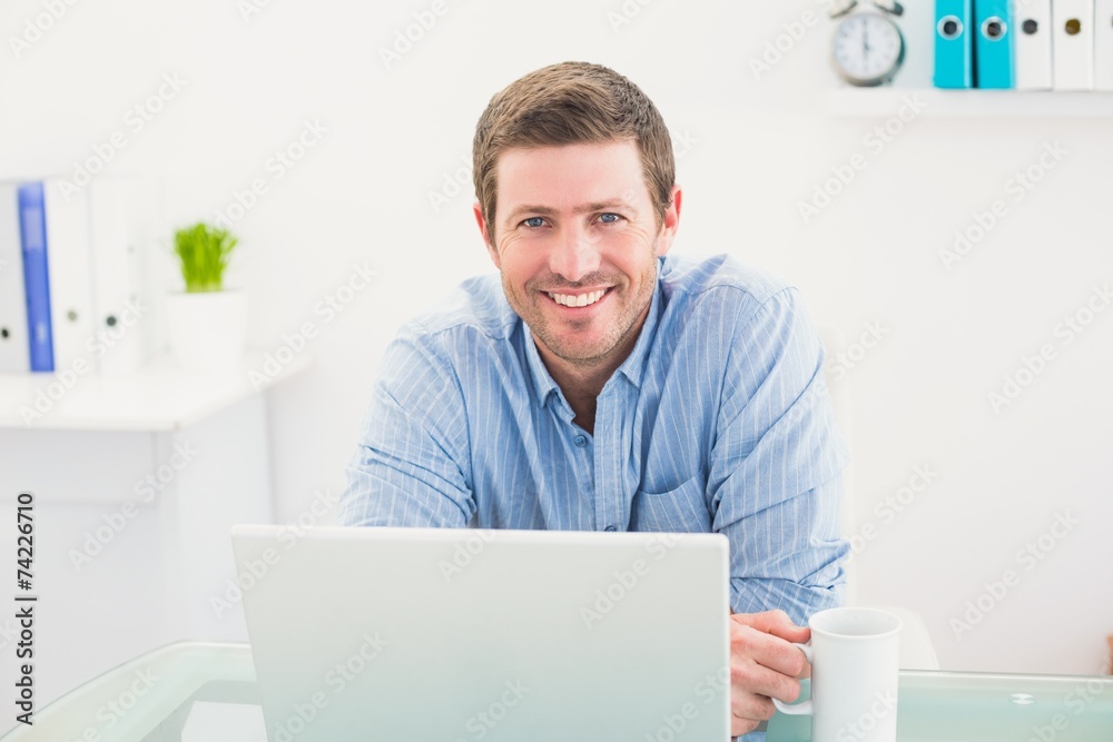 Smiling businessman holding mug at desk