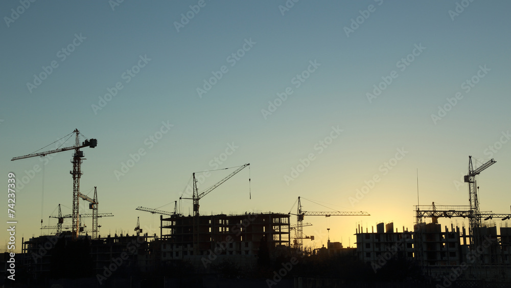 silhouettes of construction  and power lines at sunset