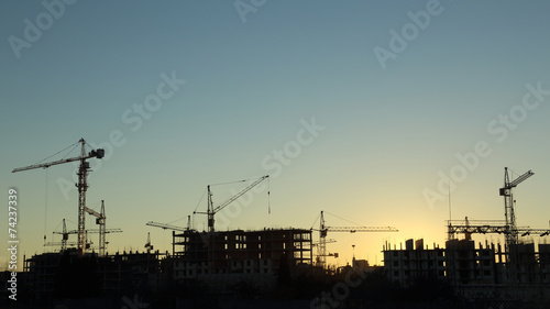silhouettes of construction and power lines at sunset