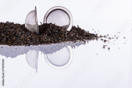 Black tea and tea strainer on white background.