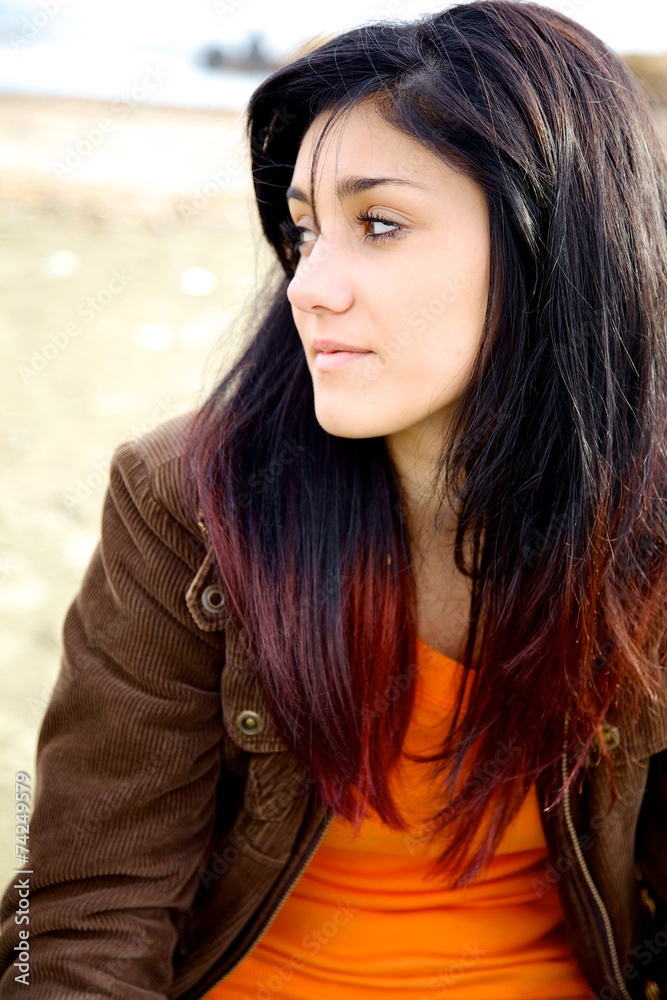 Girl thinking sitting on beach with red and black hair Girl thinking sitting on beach with red and black hair
