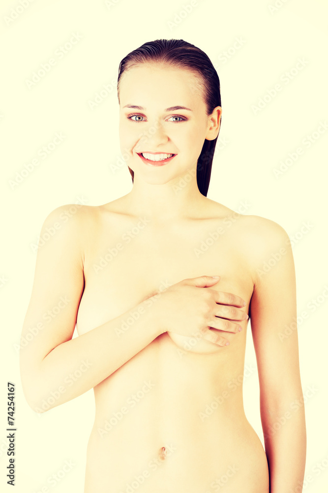 Attractive young woman holding breast. Front view.