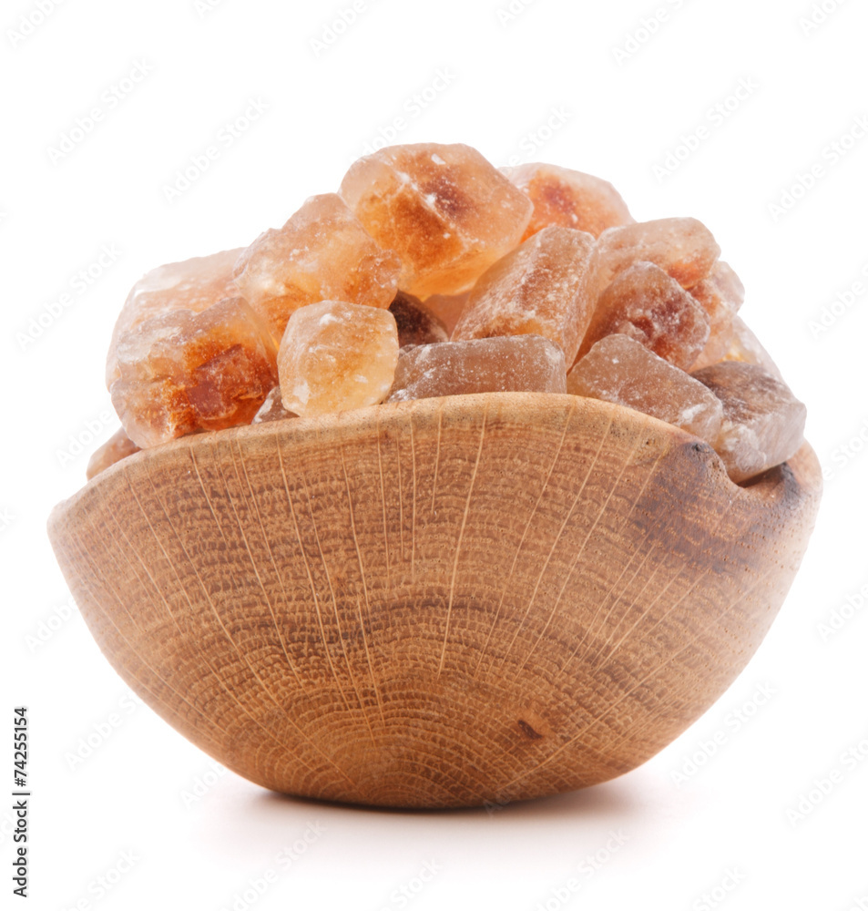 Brown cane caramelized lump sugar in wooden bowl isolated on whi