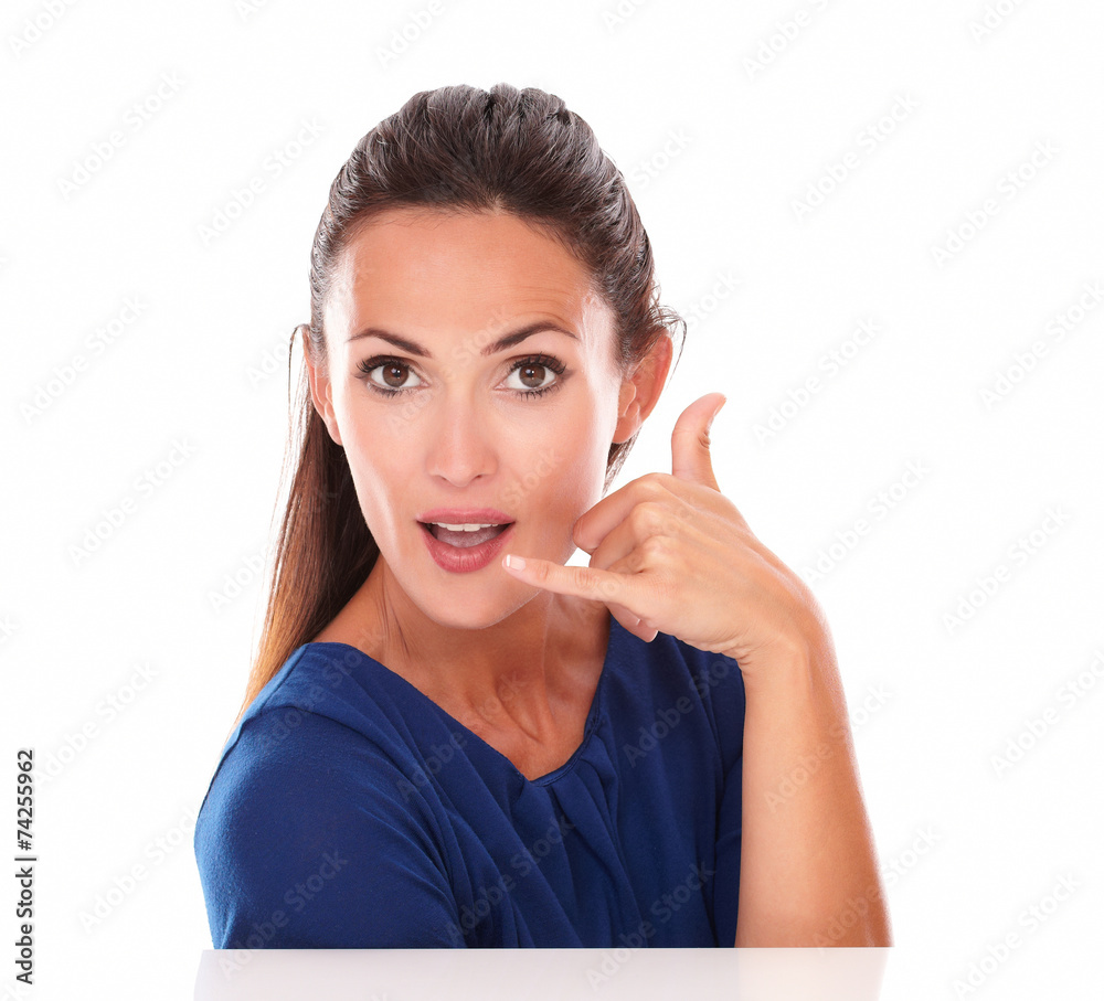 Young female in blue blouse gesturing a call Young female in blue blouse gesturing a call