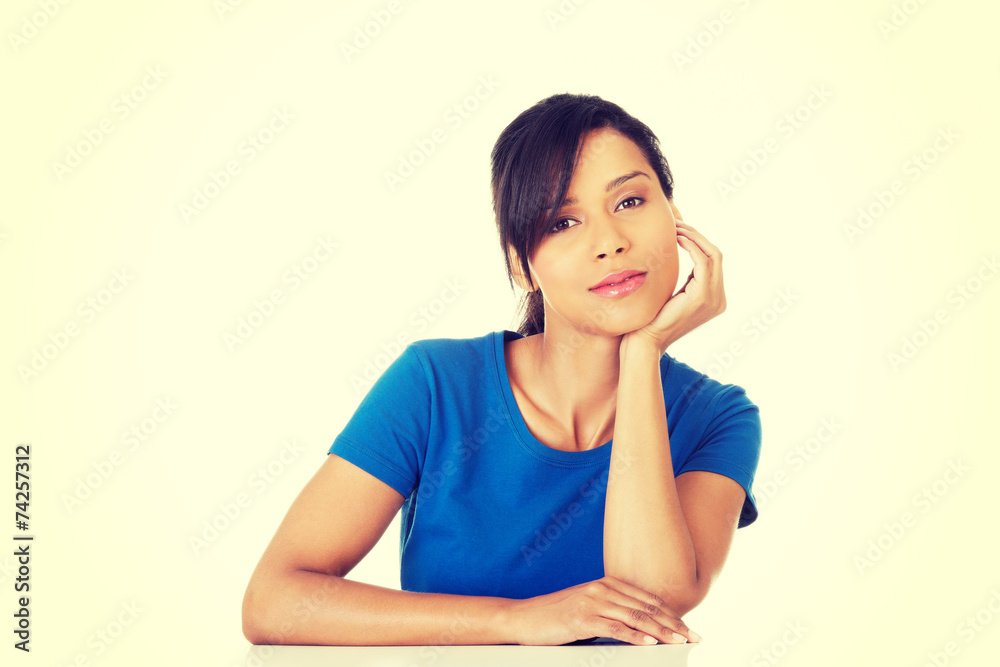 Pretty, happy, young woman in casual clothes sitting at the desk Pretty, happy, young woman in casual clothes sitting at the desk