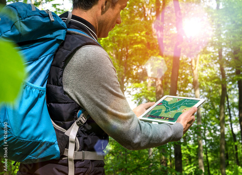 Wanderer mit Tablet-PC beim Wandern Wald Gegenlicht